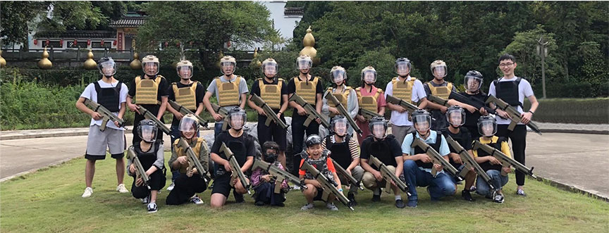 Un groupe de personnes équipées d'un équipement de protection et tenant un équipement de laser tag, prêtes pour un match en plein air.