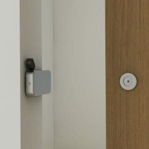 Una porta del fienile vista di lato, leggermente socchiusa, con una serratura per porta scorrevole interna Privacy e un foro per sbirciare sulla superficie in legno.