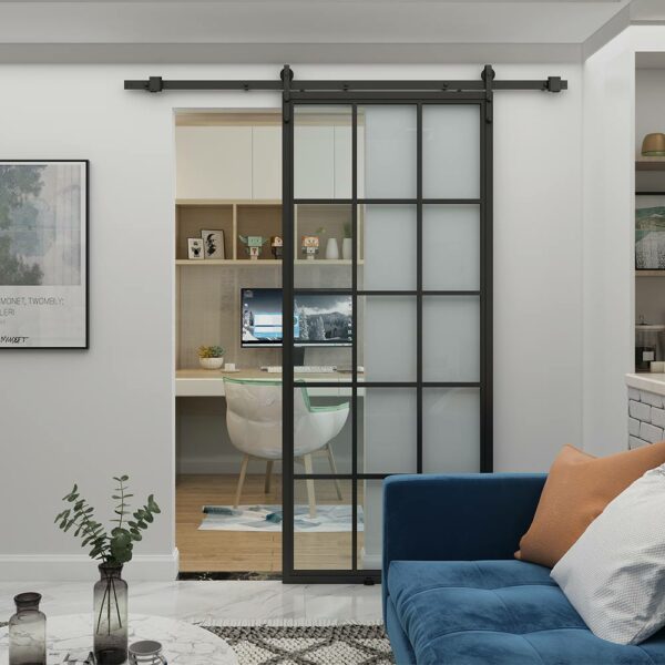 Home office moderno con porta scorrevole in vetro, adiacente ad una zona soggiorno con divano blu.