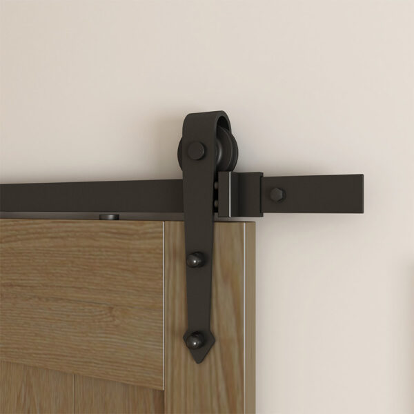 A sliding wooden door mounted on a black metal track with Arrow Barn Door Hardware attached to the top, set against a beige wall.