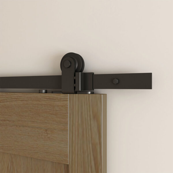 A sliding barn door with a modern black hardware mechanism mounted to a beige wall.