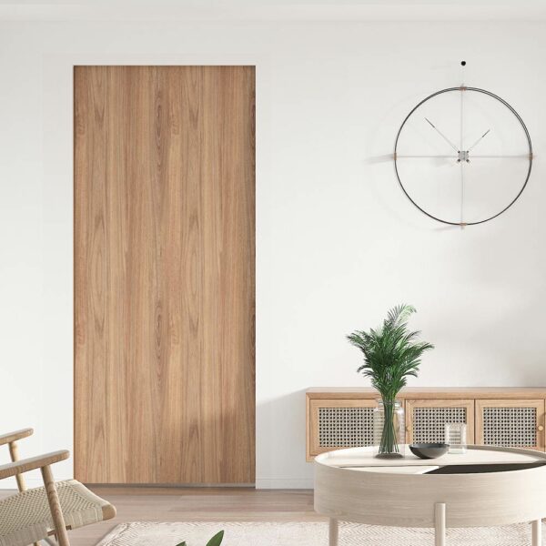 Ett minimalistiskt vardagsrum med en stor gömd bana i trä med skjutbara tunga fickdörrar med kraftig hårdvara, en rund väggklocka, två skåp och en liten planta på ett runt bord.