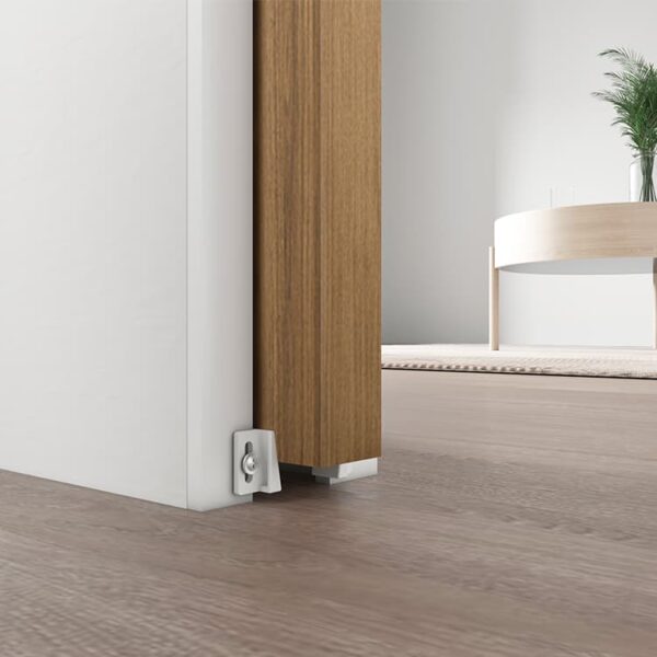 A partially open wooden door with Pocket Door Hardware Kit in a modern room featuring light brown flooring and a plant in the background.