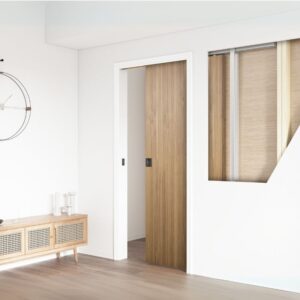 A minimalist room with a wooden sliding door using a Pocket Door Kit, a wall clock, and a sideboard on the smooth floor.