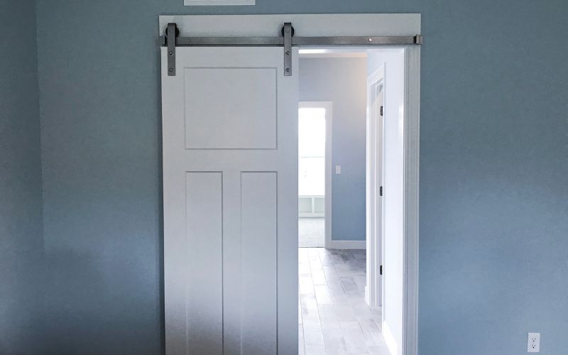 Sliding barn door open to a room with a traditional doorway visible in the background.