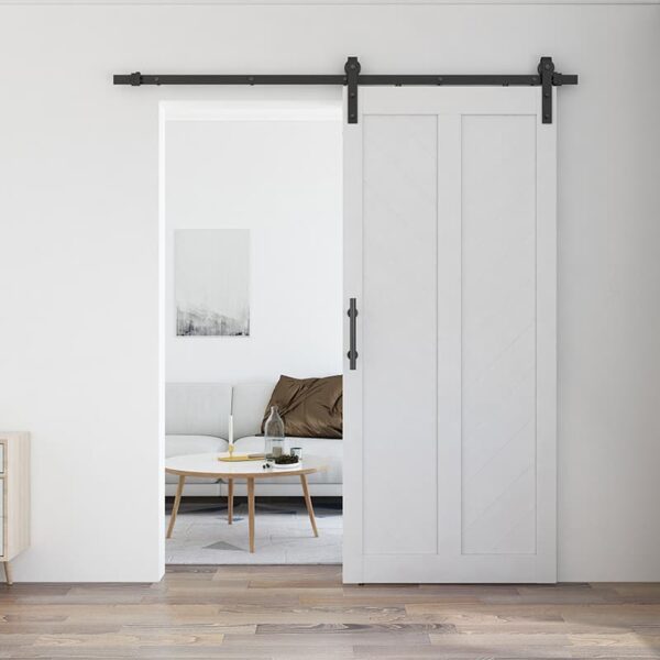 A modern living room with a sliding 36in x 84in White Chevron Barn Door, 5 Lites, DIY Assembly, Knocked Down Version open to reveal a cozy interior with a sofa, cushion, and a coffee table.