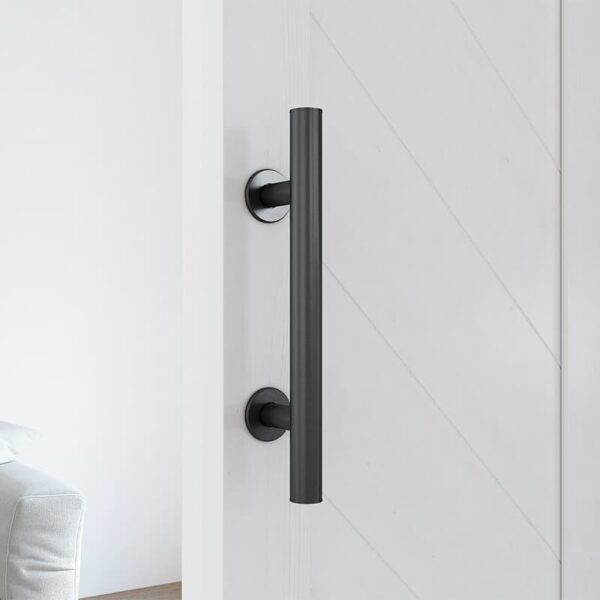 A modern, vertical black door handle on a 36in x 84in white chevron barn door with 5 lites in a minimalist interior.