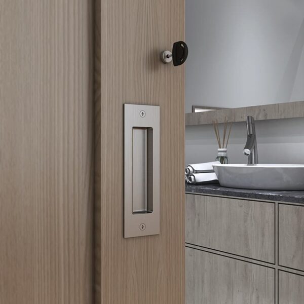 Modern bathroom with a slightly open soft-closing sliding door, revealing a sink and mirror, featuring stainless steel hardware.