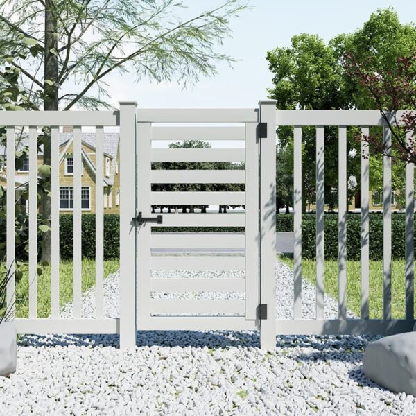 A white slatted gate with a latch stands between two picket fence sections, surrounded by gravel and greenery, with houses in the background.