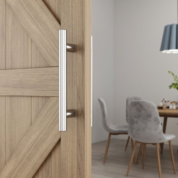 A close-up of the Stainless Steel Barn Door Handle reveals its rustic charm, contrasting with a welcoming dining area beyond.