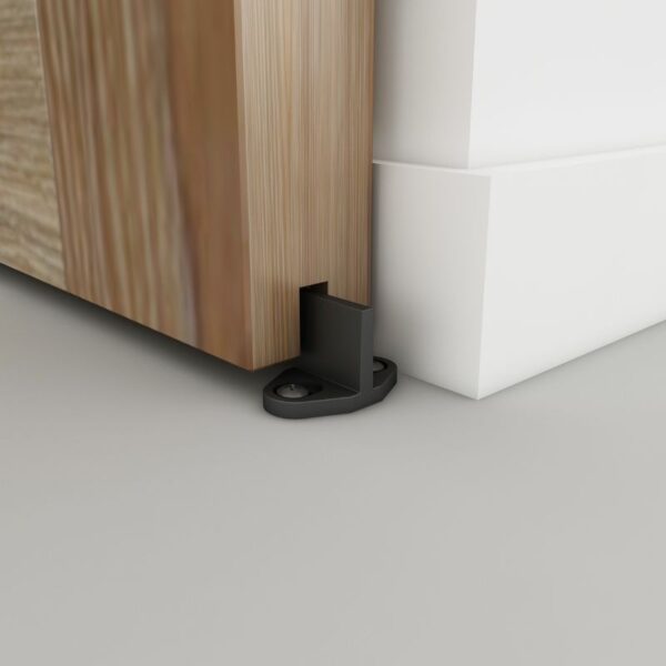 A wooden door with a floor-mounted black stopper prevents it from hitting a white wall.