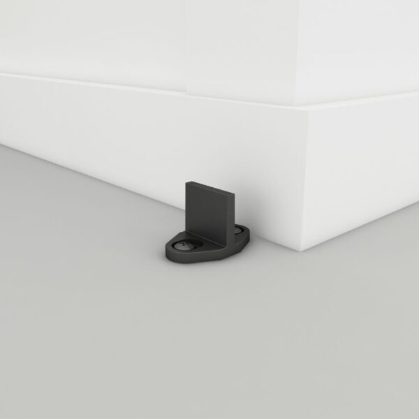 Black door stopper on a light gray wall corner above a gray floor.