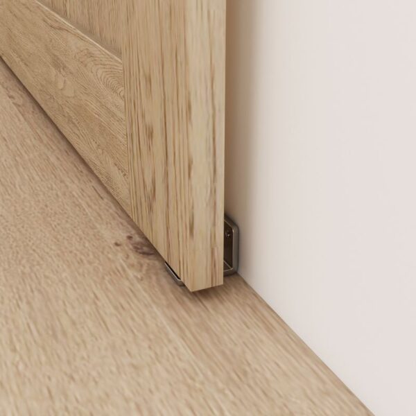 Close-up of a wooden barn door with a Premium Brushed Nickel Floor Guide. The open door contrasts strikingly with the light floor.