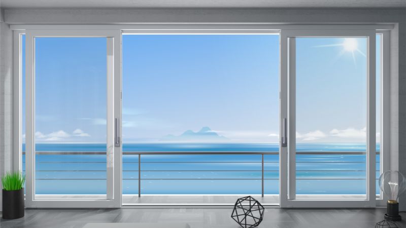 Expansive glass doors reveal railing, azure ocean, distant islands, sunny sky. Inside, a plant complements geometric decor.