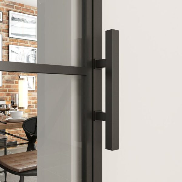 A modern black handle on a steel-framed sliding frosted glass barn door reveals a brick-walled room with a table, chairs, and art.