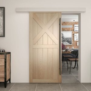 A barn door with a black stainless steel handle opens to reveal a brick-walled room with a table, chairs, and camera on the cabinet.