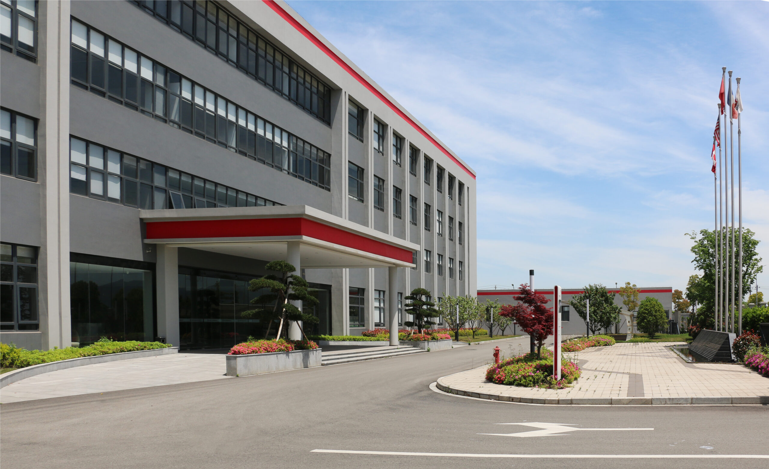 Choisissez notre bâtiment industriel avec de grandes fenêtres, une verrière rouge et un environnement paysager pour la fonctionnalité et l'esthétique.