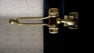 Close-up of a gold door latch on a frame beside textured wallpaper—an example for door latch guides.