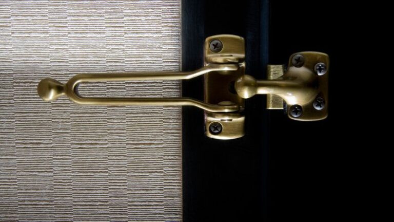 Gros plan d'un loquet de porte doré sur un cadre à côté d'un papier peint texturé - un exemple de guides de loquet de porte.