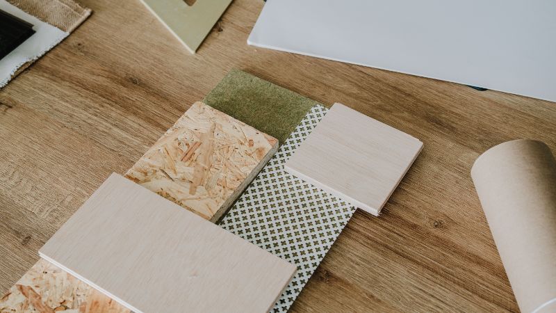 Échantillons de bois et de stratifié, échantillons de tissu et un rouleau de papier disposés pour mettre en valeur le rôle de la texture dans la décoration intérieure.
