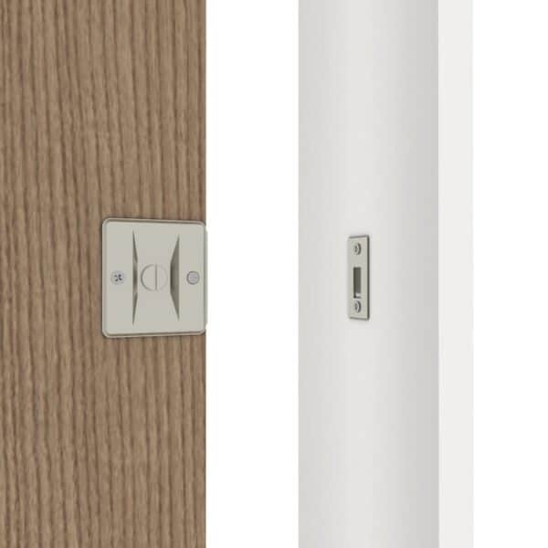 Gros plan d'une serrure de porte coulissante en nickel brossé sur une porte en bois, avec une plaque de verrouillage assortie sur un cadre blanc.