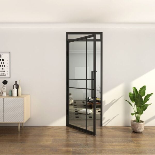 Black-framed steel & glass door with fanlight, open in modern room with wood floors, art, white sideboard, potted plant.
