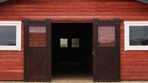 Barn door with sliding mechanism on a red wooden barn exterior.