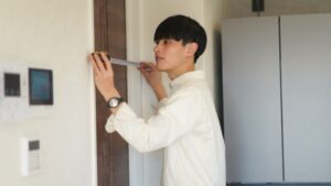 אדם מודד את משקוף הדלת להתקנת דלת האסם באמצעות סרט מדידה, תוך הקפדה על מידות מדויקות להתאמה ותפקוד נאותים.