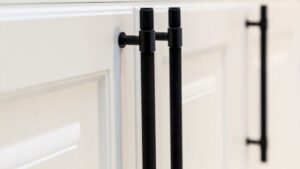 Close-up of black barn door handles installed on a white sliding barn door, showcasing handle placement on both sides for easy access and secure operation.