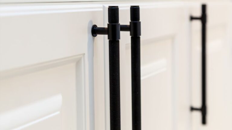 Close-up of black barn door handles installed on a white sliding barn door, showcasing handle placement on both sides for easy access and secure operation.