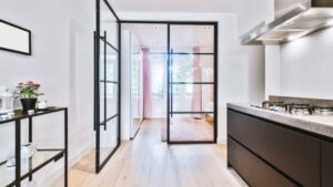 Bright modern kitchen featuring a glass partition, sleek black cabinetry, and ample natural light, creating an open and inviting space for cooking and entertaining.