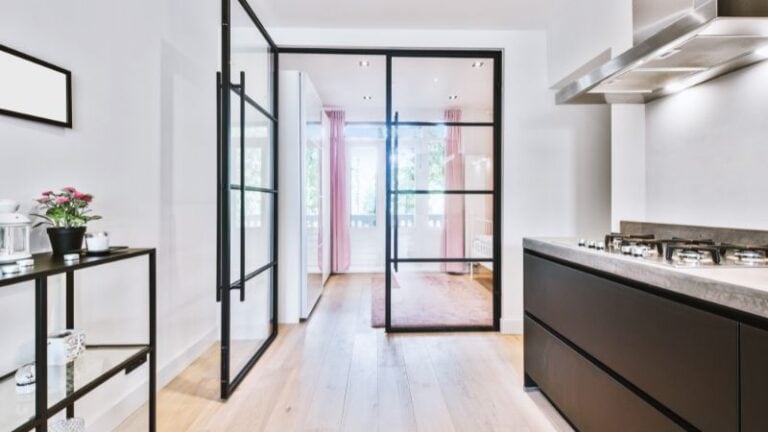 Bright modern kitchen featuring a glass partition, sleek black cabinetry, and ample natural light, creating an open and inviting space for cooking and entertaining.