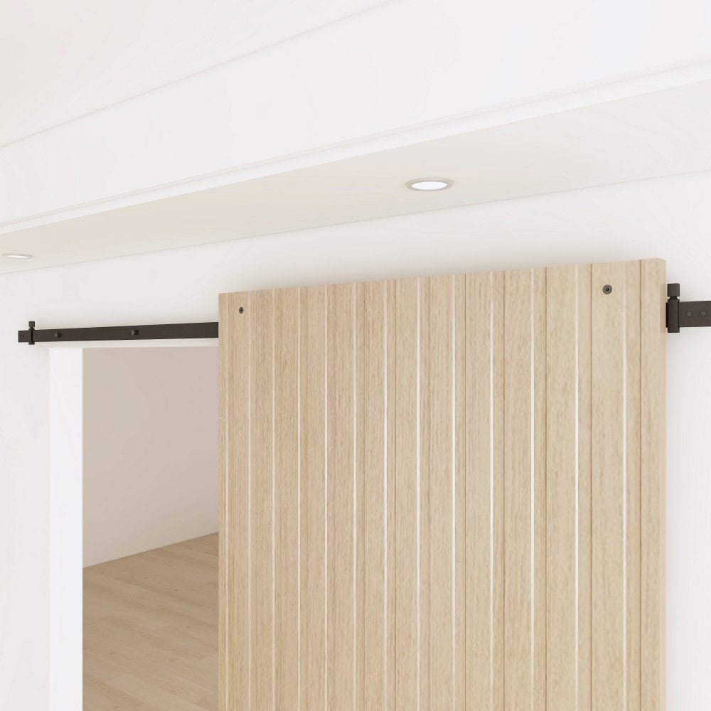 Modern sliding barn door with concealed hardware system, ideal for space-saving interior design, featuring a light wood finish and black metal track.
