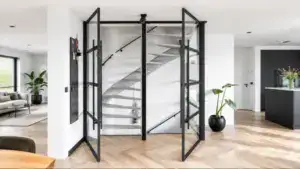 Contemporary steel-framed glass partition around a spiral staircase in a modern home interior, emphasizing sleek design and transparency.